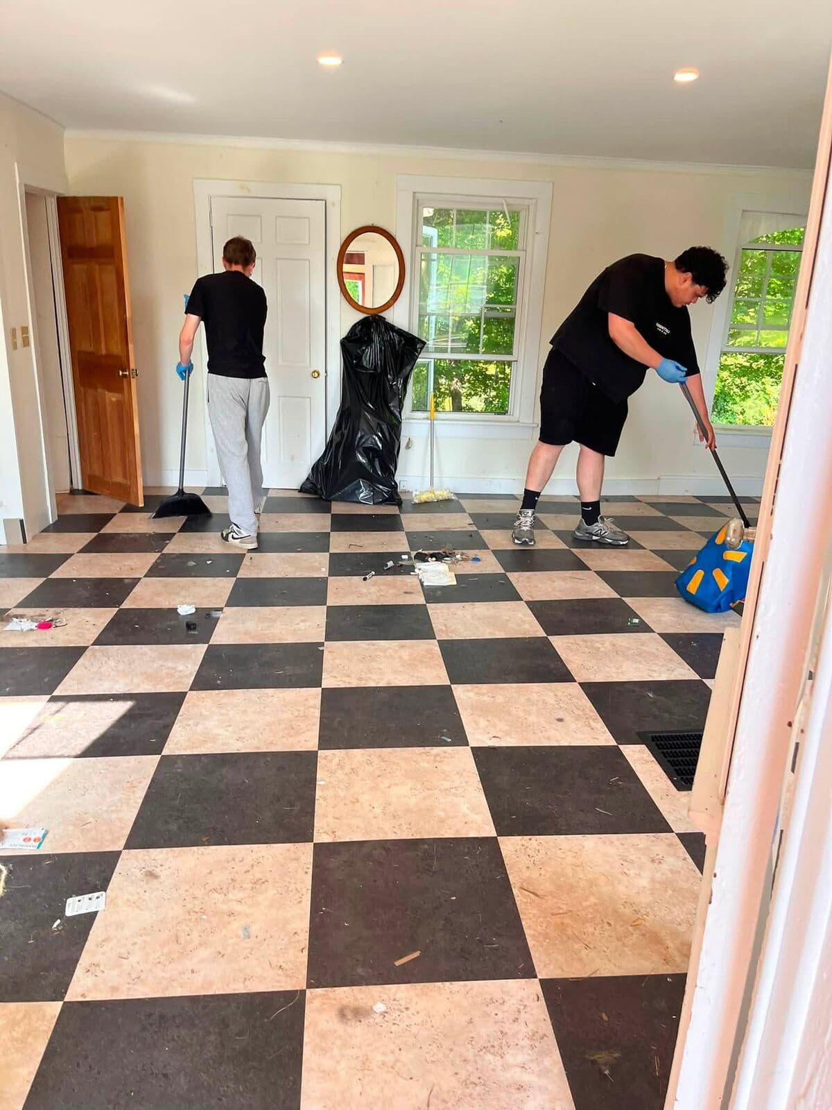 Two JC Crew members mopping a checkerboard kitchen floor
