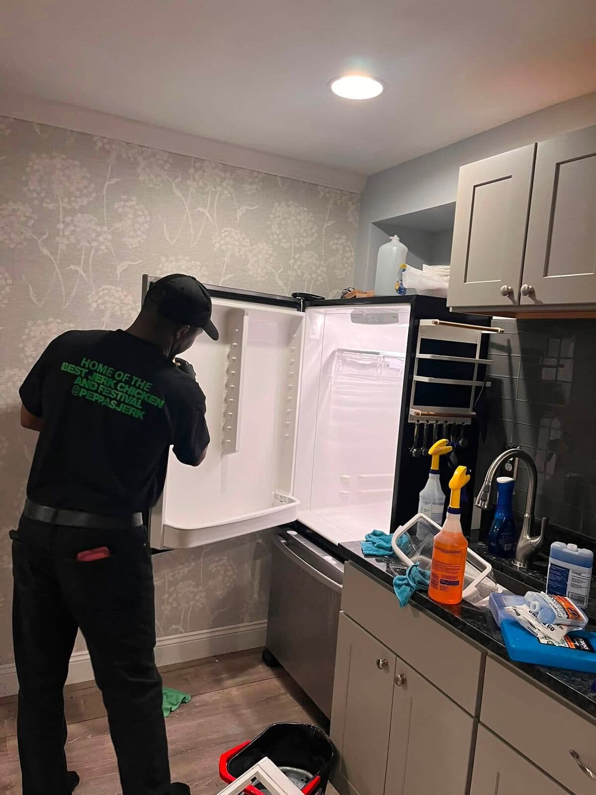 Crew member detailing a fridge in a modern kitchen